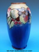 A Royal Doulton vase painted with fruit and flowers on a blue relief (26cm tall)