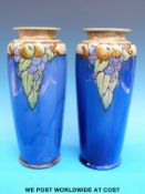 A pair of Doulton Lambeth tapered vases with apple and grape design on blue ground (26cm tall)