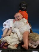 A collection of dolls to include a black headed example with closing eyes and smaller examples with