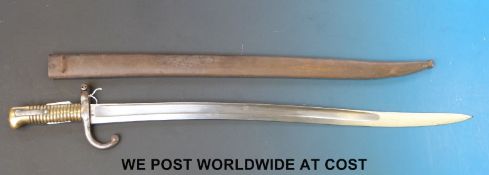 A late 19thC French bayonet in scabbard, D98352 to hilt, with brass handles and curved quillon,