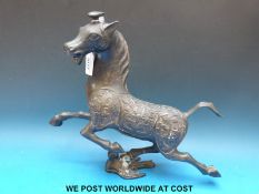 A Chinese patinated bronze horse decorated with auspicious astride a swallow