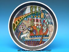 A studio pottery shallow bowl with suspension loop decorated with abstract garden scene,