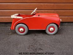 A vintage metal pedal car with two speed control finished in red and cream stamped Lieway