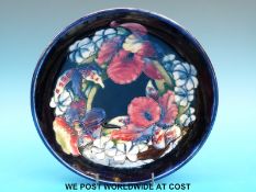 A Moorcroft footed bowl decorated in Iris pattern on blue ground,