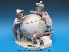 A Lladro figural group of three children studying a large globe (23cm tall)