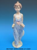 A Lladro child figure with flowers in the pockets of her dungarees (26cm tall)