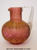 An unusual cranberry glass jug possibly by James Powell with applied ribbed decoration and further