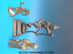 An Indian brass figure of Krishna dancing on top of a snake together with two other brass figures