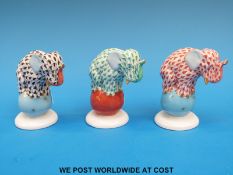 Three Herend elephants standing on balls, fishnet design, one black on a blue ball,