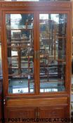 An ornate Chinese display cabinet with carved decoration to the top and storage space below with