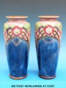 A pair of Doulton Lambeth vases with rose design on a blue ground (26cm tall)