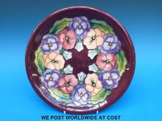 A Moorcroft charger decorated in the Pansy pattern (26cm diameter)