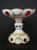 Bohemian overlaid glass tazza with painted floral sprays and gilt decoration on a cranberry ground