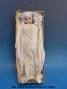 A miniature bisque headed doll in period clothing