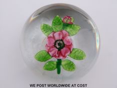Clichy glass paperweight featuring a central pink and green flower with green foliage (6.