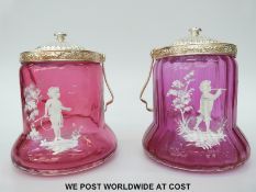 A pair of Mary Gregory cranberry glass biscuit barrels with silver plated rims and handles and