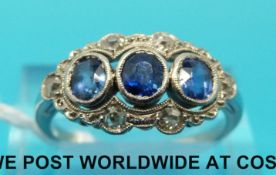 A white metal ring (believed to be platinum) set with three oval sapphires surrounded by diamonds