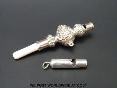 A small white metal dog or child's whistle, length 3cm together with a further baby's rattle,