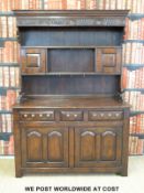 A 19thC style carved and panelled oak dresser with two small cupboards above three straight drawers
