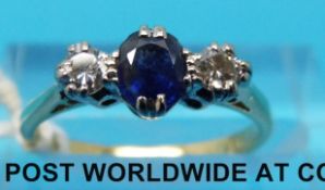 An 18ct gold ring set with an oval sapphire flanked by diamonds (size I/J)