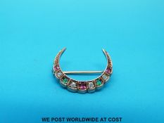 An Edwardian yellow metal brooch marked 9ct gold, of crescent shape set with emeralds,
