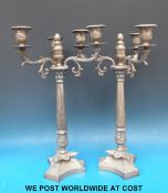 A pair of silver plated candelabrum with ornate decoration on triform bases (height 48cm)