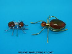 A yellow metal brooch set with amber in the form of a spider and a smaller silver example