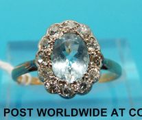 An 18ct gold ring set with an oval aquamarine surrounded by diamonds (size N)