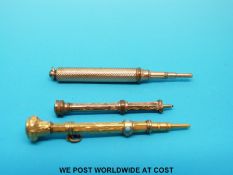 Three yellow metal miniature propelling pencils, one with intaglio finial,