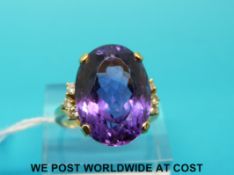 A yellow metal ring marked 18ct set with a large oval cut amethyst with three diamonds to each side