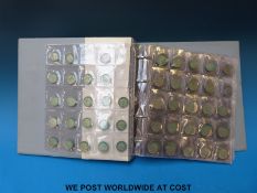 A collection of UK coinage in a folder including pre-1920 and pre 1947 silver George III crown,