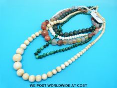 A collection of necklaces including agate, ivory, malachite and an example with a gold clasp,