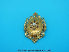 A yellow metal pendant marked 18ct gold set with a pearl to the centre surrounded by sapphires with