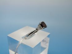 A platinum ring set with a laboratory grown red diamond of approximately 0.