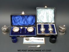 A cased pair of hallmarked silver peppers and a cased pair of silver open salts and spoons,