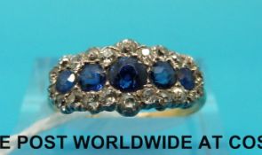An 18ct gold ring set with five graduating sapphires surrounded by diamonds (size N)