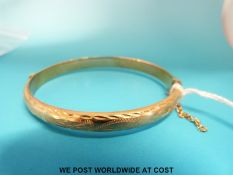 A 9ct gold bangle with chased decoration (8.