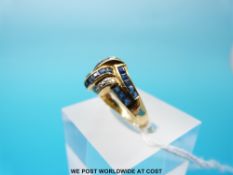 A yellow metal ring set with diamonds and sapphires in a cross over design, marked 750 (size N, 3.