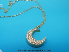 A 14ct gold crescent shaped pendant set with cubic zirconia on a 14ct gold chain