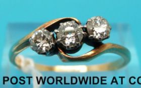 A yellow metal ring set with three diamonds in a twist setting, the largest approximately 0.
