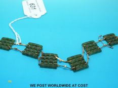 A yellow metal bracelet set with square pierced sections of spinach jade separated by bars of