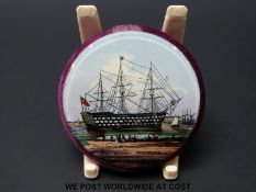 A 19thC pin cushion with reverse decorated glass plaque of HMS Victory and a mirror verso, 4.