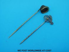 A yellow metal horse's hoof stick pin and a bicycle stick pin