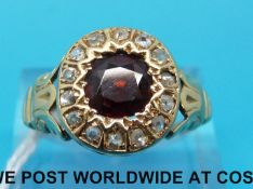 A Victorian yellow metal ring set with a round cut garnet surrounded by rose cut diamonds (size V)