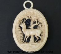A 19thC French bone pin cushion, finely carved with a stag in a glade and a geometric leaf pattern,