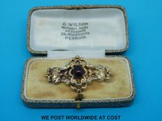 A yellow metal brooch set with a garnet cabochon