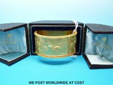 A Victorian yellow metal bangle with Japanese style design depicting storks and bamboo,