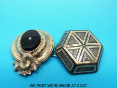 A brooch inlaid with silver and gold and another brooch set with oynx and a seed pearl.