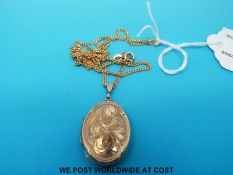A 9ct gold locket with chased decoration on a 9ct gold chain (9g)