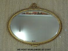 A 19thC oval mirror with gilt plaster work and wooden frame ornately decorated with ribbon twist